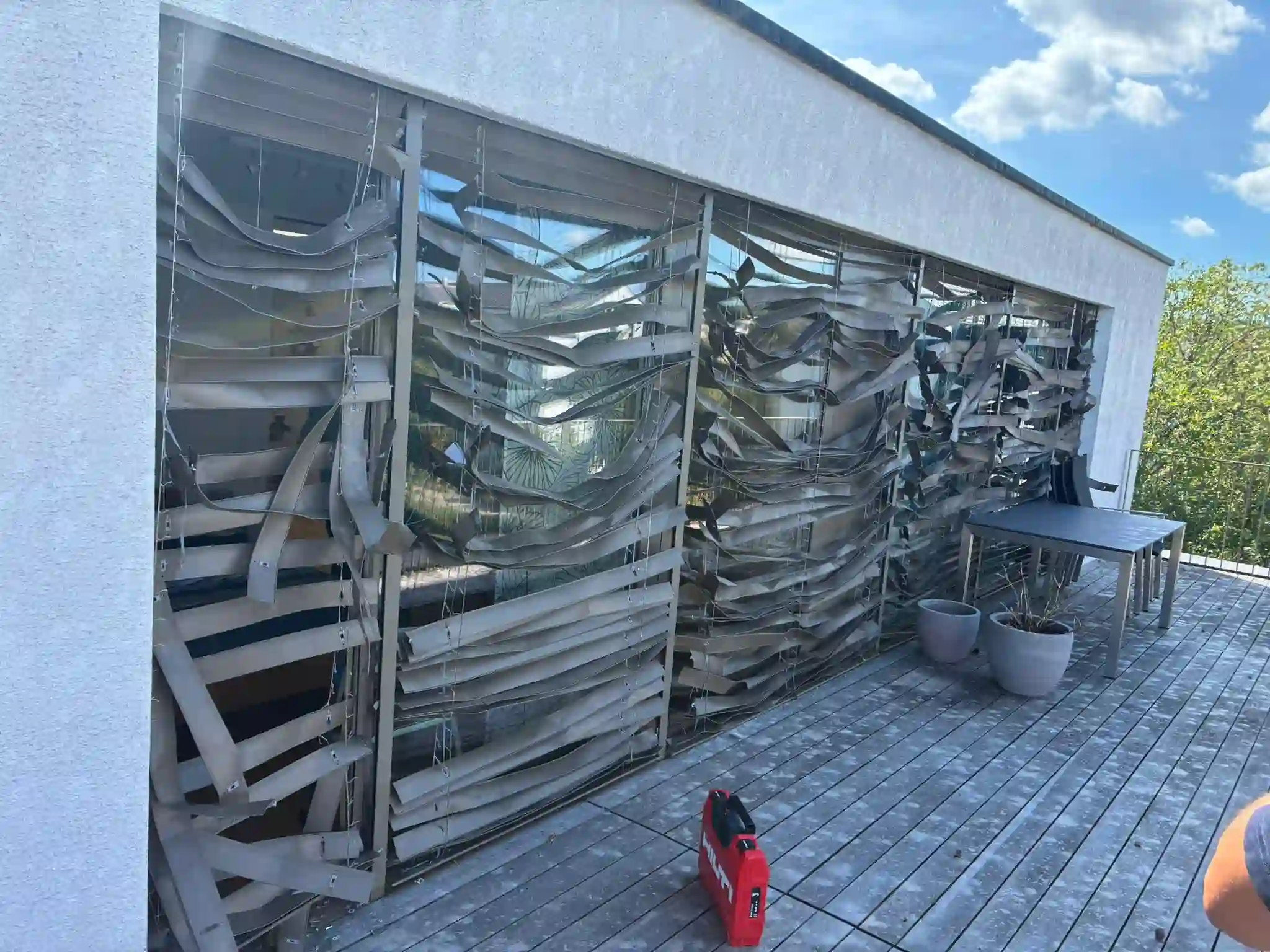 Durch Sturm verbogene und verdrehte Lamellenstoren an einer Terrassenfassade in Winterthur